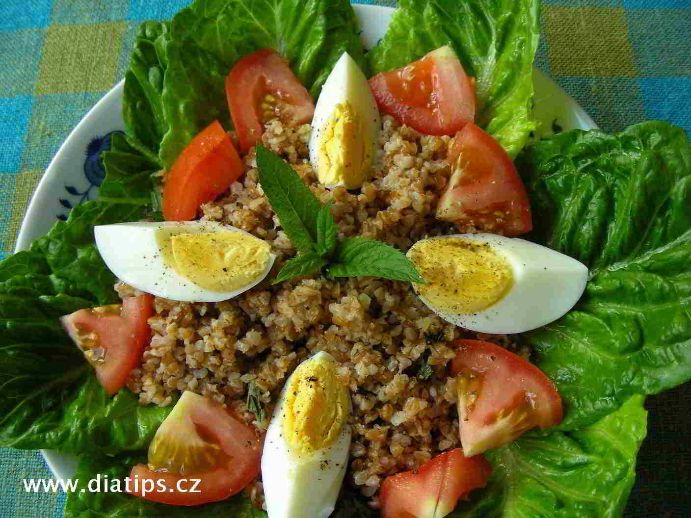 Bulgurový salát s vejci a rajčetem na talíři vyloženém hlávkovým salátem