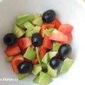 Lehký salát s avokádem a olivami v misce na stole